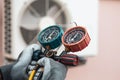 Mechanic air conditioner technician using manifold gauge checking refrigerant for filling home air conditioning and air duct Royalty Free Stock Photo