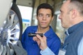 Mechanic with apprentice inspecting wheel with torch Royalty Free Stock Photo