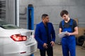 Mechanic in apron talking to a customer about a car repair Royalty Free Stock Photo