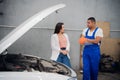 A mechanic asks a woman about a car repair