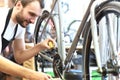 Mechanic in a bicycle repair shop oiling the chain of a bike