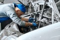 Mechanic in blue overalls checking serviceability of car engine Royalty Free Stock Photo