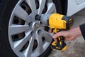 Mechanic changing a car tire in a workshop using an electric drill to loosen the bolts in a concept of service or replacement car Royalty Free Stock Photo