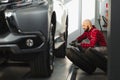 Mechanic changing a car tire in a workshop on a vehicle on a hoist using an electric drill to loosen the bolts in a concept of Royalty Free Stock Photo