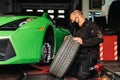 Mechanic changing the wheels of a high-end super sports car. Auto mechanic working in garage. Repair service. Royalty Free Stock Photo