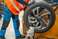 Mechanic checking balanced car wheel manually on a balancing machine before installation. Final inspection step during Royalty Free Stock Photo