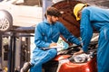 Mechanic checking the opened hood car with his assistant. Auto car repair service center. Professional service