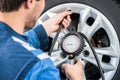 Mechanic Checking Tire Pressure With Gauge