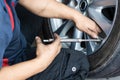 Mechanic checking tire pressure with tyre pressure gauge Royalty Free Stock Photo