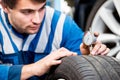 Mechanic, checking the wear on the tread of a tire