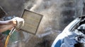 Mechanic cleaning dirty car air filter with air blow gun. The mechanic is blowing the filter of the car.  Car maintenance service Royalty Free Stock Photo