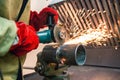 mechanic cleans a welded seam on a section of a steel a grinding machine in the metal workshop