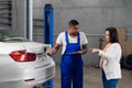 Mechanic with clipboard discusses car repair with client Royalty Free Stock Photo