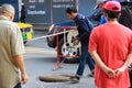 A mechanic is closing a large steel manhole cover. There were many people standing and watching