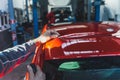 Mechanic customizes car removing spoiler using cutting cord in auto repair shop