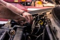Mechanic with dirty hands works on car engine. Authentic shot of real auto mechanic working on motor