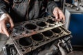 Sealing gasket in hand. The mechanic disassemble block engine vehicle. Engine on a repair stand with piston and