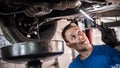 Mechanic discharges motor oil from engine tank under the car