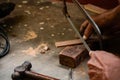 A mechanic does carpenter jobs with wood, plus and other tools. He is hitting hammer on the head of nail to wooden pieces and