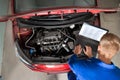 Mechanic Examining Car Engine With Help Of Laptop Royalty Free Stock Photo