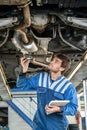 Mechanic Examining Exhaust System Of Car With Flashlight Royalty Free Stock Photo