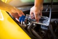 Mechanic fill fresh water into windscreen or in water tank wiper on yellow car  engine room Royalty Free Stock Photo