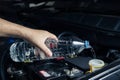 The mechanic fills water in the car's inspection tank and inspects the engine before starting the car maintenance trip. Royalty Free Stock Photo