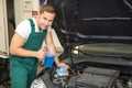 Mechanic fills coolant or cooling fluid in motor of a car