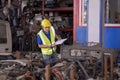 A mechanic or a foreman is checking the stock of used car parts in a warehouse