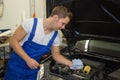 Mechanic in garage checking motor oil level at a car Royalty Free Stock Photo