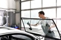 Mechanic in a garage replaces defective windshield of a car Royalty Free Stock Photo