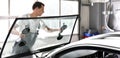 Mechanic in a garage replaces defective windshield of a car Royalty Free Stock Photo