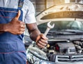 Mechanic hand checking and fixing a broken car in garage.hand of mechanic with thumbs up and tool. Royalty Free Stock Photo