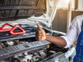 Mechanic hand checking and fixing a broken car in garage.hand of mechanic with thumbs up and tool. Royalty Free Stock Photo