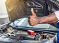 Mechanic hand checking and fixing a broken car in garage.hand of mechanic with thumbs up and tool. Royalty Free Stock Photo