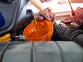 Mechanic hand pouring fresh engine oil through orange funnel into the car engine