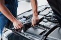 Mechanic hands checking up of serviceability of the car in open hood, close up. Royalty Free Stock Photo