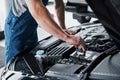 Mechanic hands checking up of serviceability of the car in open hood, close up. Royalty Free Stock Photo