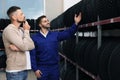 Mechanic helping client to choose car tire in store Royalty Free Stock Photo