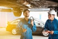 Mechanic and his assistant examining the car bottom with flash light. Auto car repair service center. Professional service Royalty Free Stock Photo