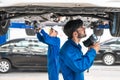 Mechanic and his assistant examining the car bottom with flash light. Auto car repair service center. Professional service Royalty Free Stock Photo