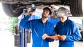 Mechanic and his assistant examining the car bottom with flash light. Auto car repair service center. Professional service Royalty Free Stock Photo