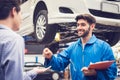 Mechanic holding clipboard giving the key back to car owner in the workshop garage. Car auto services concepts Royalty Free Stock Photo