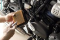 Mechanic holding dirty Engine Air Filter over motorcycle and cleaning Filter with air blow gun .mechanic working in garage. Repair Royalty Free Stock Photo