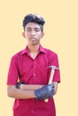 Mechanic holding a hammer tool and cross arms on yellow background