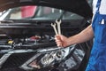 Mechanic holding pair of wrenches at the repair garage