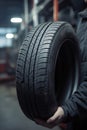 Mechanic holding a tire at the repair garage, Replacement of winter and summer tires AI generated