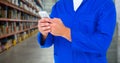 Mechanic holding up phone against blurry warehouse Royalty Free Stock Photo