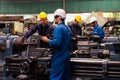 Mechanic holding a wrench and a tablet standing in front of an machine. Engineers and skilled technicians are looking forward