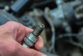 a mechanic holds a car engine spark plug in his hand Royalty Free Stock Photo